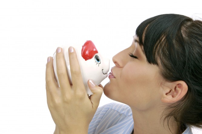 junge Frau kuesst ihr Sparschwein, young woman kissing piggybank