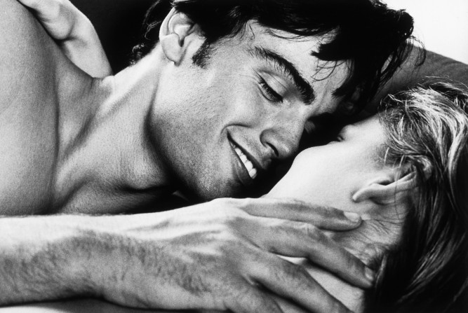 smiling naked couple lying on bed