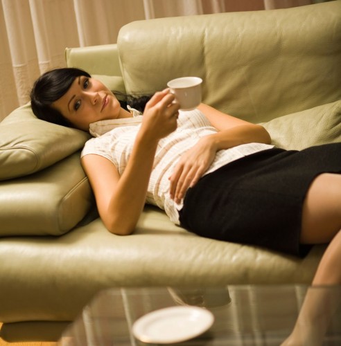 Young woman in living room drinking tea and having a nap