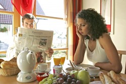 Paar beim together, togethernessen Fruehstueck er liest Zeitung sie ist sauer, couple having breakfast together he reads newspaper she is annoyed